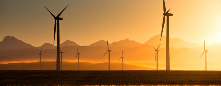 Wind turbines set against a sunset sky