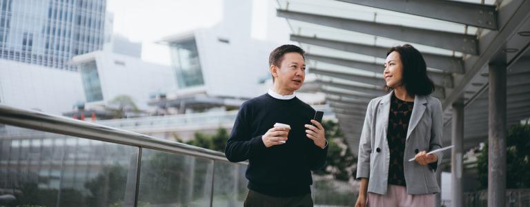 A business man and woman walking with a city backdrop