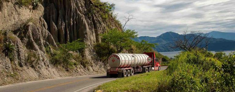 A tank truck drives along a mountain road.