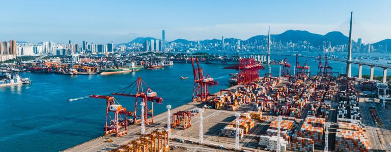 An aerial view of a container ship terminal near city buildings in Hong Kong.