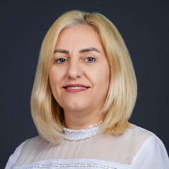 woman with blond hair wearing a white top and smiling