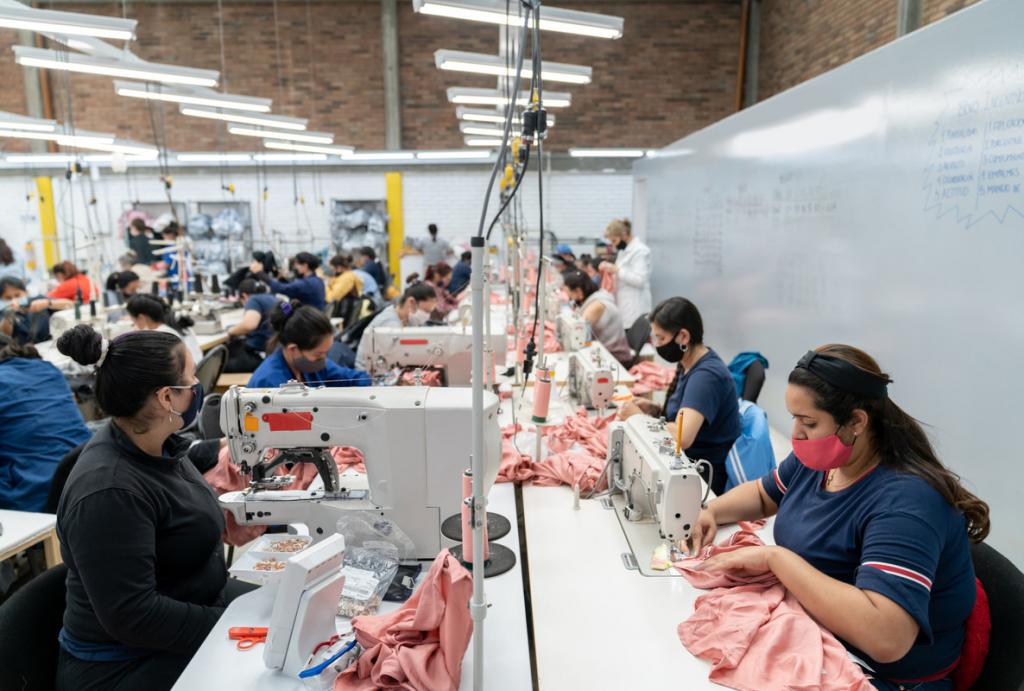 Women working at industrial sewing machines making pink garments